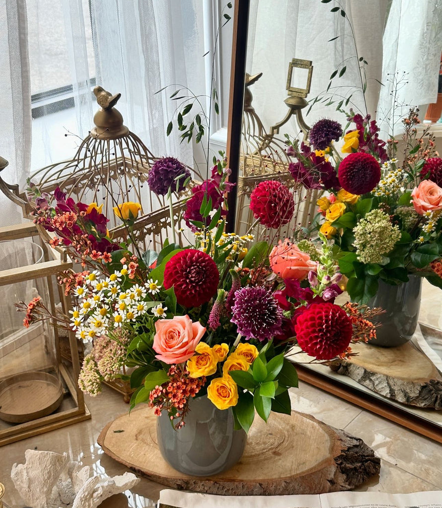 Fall Garden Wild Flower Arrangement by La Belle Fleur in a grey vase on a wood slab in front of a mirror