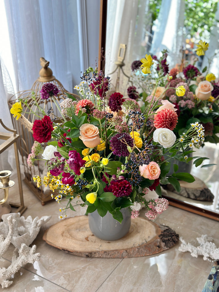 Fall Garden Wild Flower Arrangement by La Belle Fleur with a large display of wild flowers in a grey vase on a wood slab