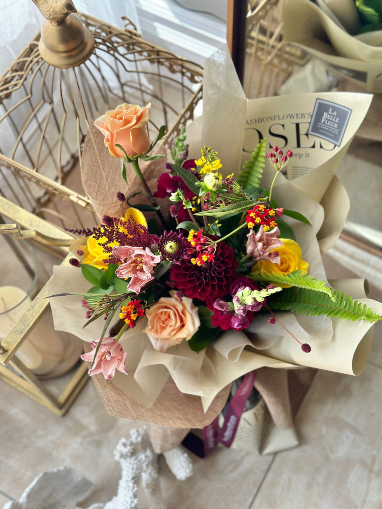 photo-of-La-Belle-fleur-s-sunrise-fall-flower-bouquet-with-colourful-mixed-flowers-wrapped-in-paper-surrounded-by-decor