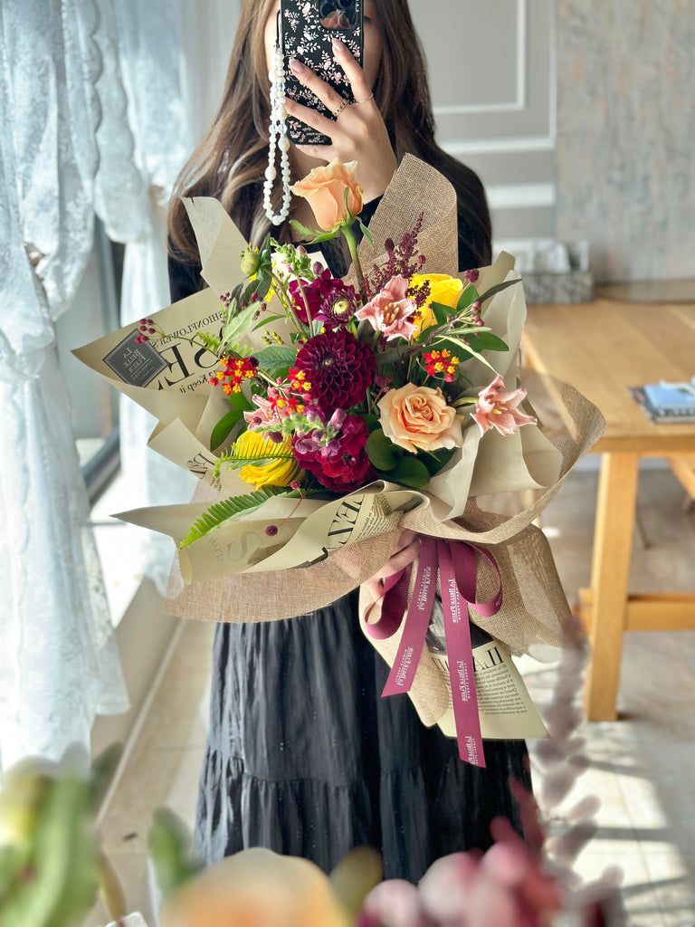 photo-of-a-girl-taking-a-picture-of-La-Belle-fleur-s-sunrise-fall-flower-bouquet-with-colourful-mixed-flowers-wrapped-in-paper