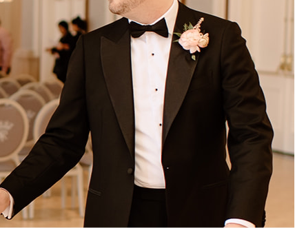 Man wearing a black tuxedo at a wedding with pink boutonnieres