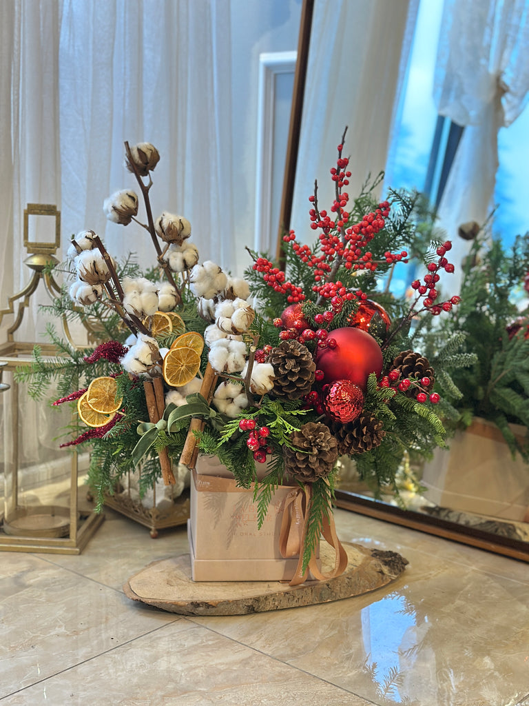 Photo of a festive winter arrangement with holiday decor and pine