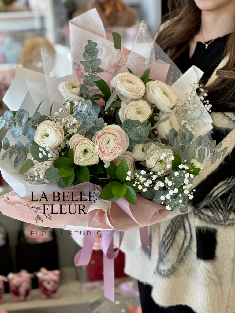Photo of a woman holding the a mixed white and pink ranunculus bouquet by La Belle Fleur
