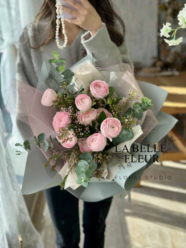 Photo of a woman holding the pink ranunculus bouquet by La Belle Fleur